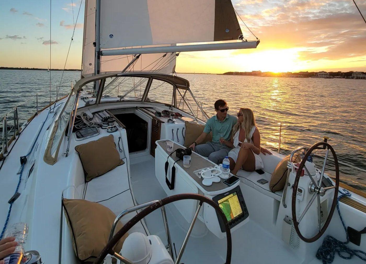 A couple watching the sunset from a sailboat on Charleston harbor